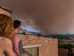 Dos vecinos observan el humo del incendio al fondo en Sant Martí de Tous, Barcelona. Este incendio permanece activo desde que comenzó el sábado por la tarde en Santa Coloma de Queralt (Tarragona).