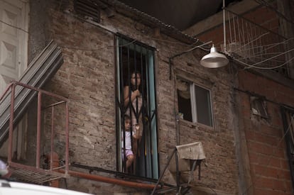 A woman and a child peer out from a doorway in Villa 31.