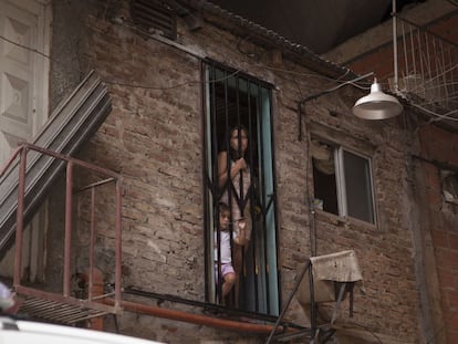 A woman and a child peer out from a doorway in Villa 31.