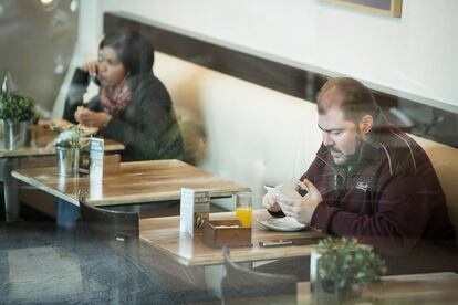 Dos personas desayunan enganchadas a sus dispositivos moviles