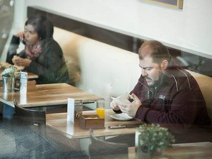 Dos personas desayunan enganchadas a sus dispositivos moviles