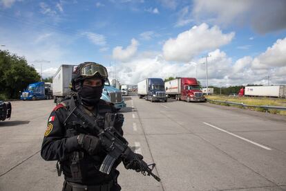 Un elemento de la policía estatal del estado de Nuevo León "Fuerza Civil"  vigila a la altura de la caseta de cobro en Sabinas Hidalgo, Nuevo León.