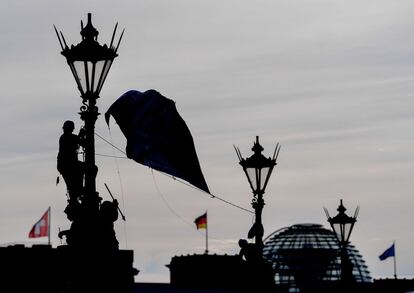 Un activista de Greenpeace escala una farola para colocar un cartel reivindicativo en contra del cambio climático en Berlín (Alemania).