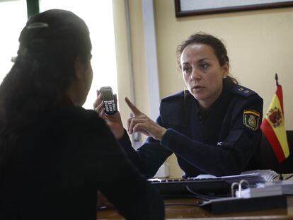 Una agente explica a una maltratada cómo usar el teléfono de emergencia.
