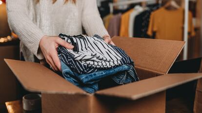 A millennial woman is preparing the shipment of some clothes in her new online shop. She's the owner of an online thrift store. New small business concept.
