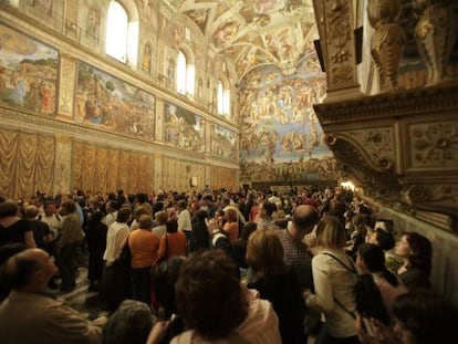 Uma multidão de turistas contempla os afrescos da Capela Sistina.