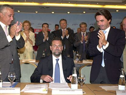 Javier Arenas y José María Aznar aplauden la elección de Mariano Rajoy como líder del PP en la reunión de ayer de la Junta Directiva del partido.