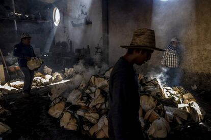 Trabajadores del palenque mezcalero Macurichos trabajan horneando pencas de mezcal en la comunidad de Santiago Matatlán, el pasado 11 de marzo.