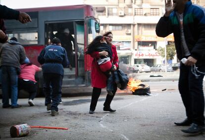 Una mujer lleva a una niña en brazos tras huir de un autobús público que fue bloqueado por los enfrentamientos entre los partidarios del depuesto presidente de Egipto, Mohamed Mursi y la policía en la parte noreste del distrito de El Cairo (Egipto).