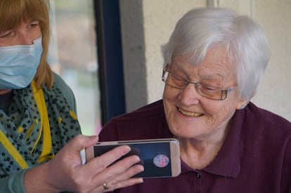 Una vecina ayuda a una anciana a hacer una videollamada.