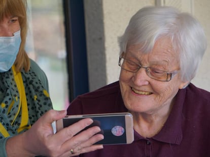 Una vecina ayuda a una anciana a hacer una videollamada. 