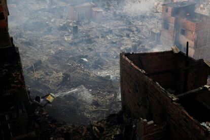 Un residente de la favela de Paraisópolis echa agua desde su casa para intentar extiguir el fuego, en Sao Paulo (Brasil).