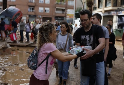 Una mujer entrega dos botellas de agua a un hombre en Paiporta, este viernes. 