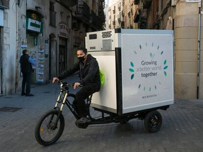 Un repartidor distribueix mercaderies congelades amb un tricicle elèctric al centre de Barcelona. 
