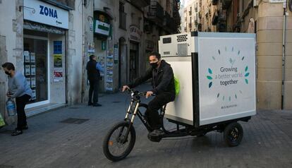 Un repartidor distribueix mercaderies congelades amb un tricicle elèctric al centre de Barcelona.
