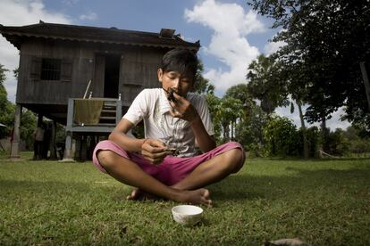 Un niño come tarántulas fritas frente a su casa, en el distrito Svay, en Kampong Thom.