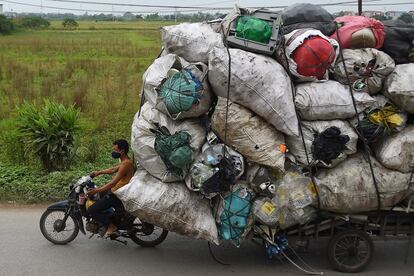 Una persona transporta residuos de plástico para su reciclaje en los suburbios de Hanoi (Vietnam).