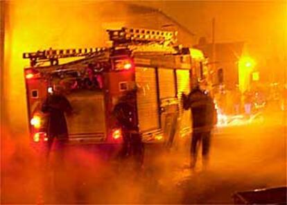 Varios bomberos intentan apagar un fuego causado durante los disturbios en Oldham, en la madrugada del lunes.