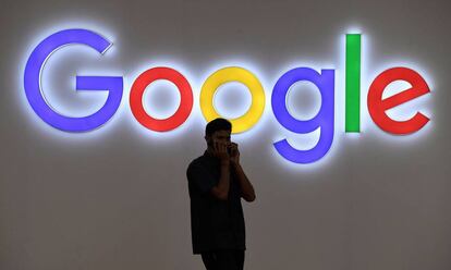 Un hombre habla por teléfono frente a un cartel de Google