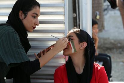 Una mujer pinta el rostro de una seguidora con la bandera de Irán para mostrar su apoyo, antes del partido de clasificación para la Copa Mundial de la FIFA entre Irán y Camboya en el estadio Azadi en Teherán (Irán), este jueves.