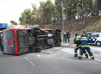 Los bomberos intentan levantar un minibús que volcó ayer en Madrid. Cuatro personas resultaron heridas.