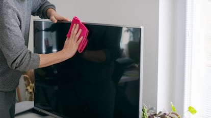 Una persona limpiando la pantalla de televisión de su casa.