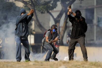 Activistas de la oposici&oacute;n venezolana lanzan piedras durante una protesta contra el gobierno del presidente Nicol&aacute;s Maduro.