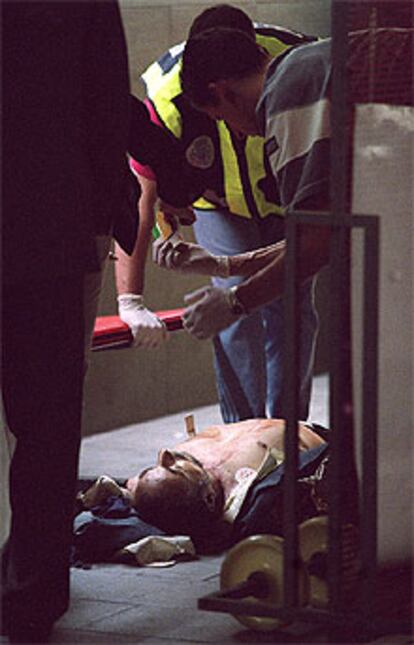 Dos policías recogen la documentación de Cándido Paredes, asesinado ayer en la estación de Recoletos.