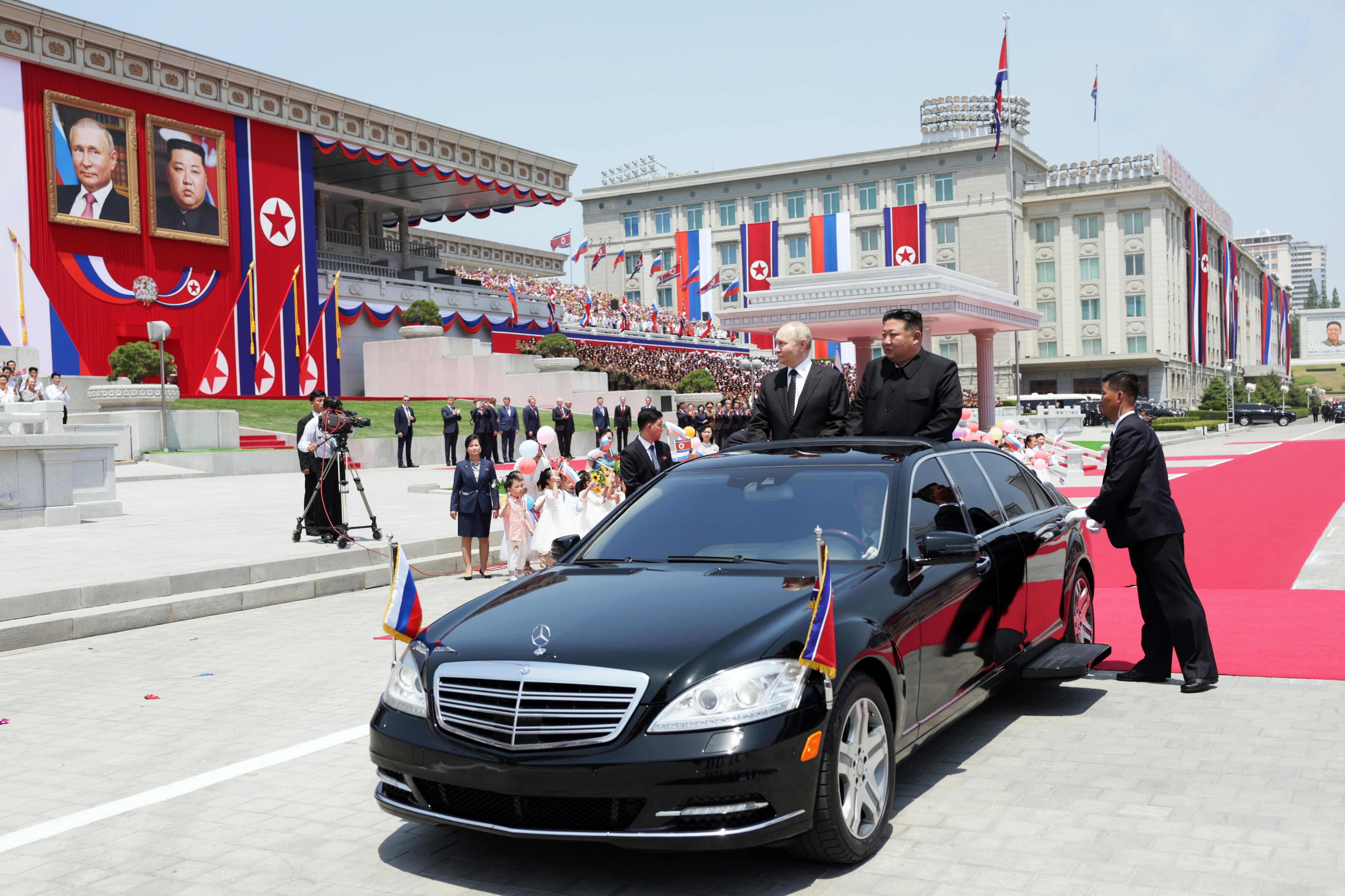 Vladímir Putin (a la izquierda) y Kim Jong-un llegan a la ceremonia oficial de bienvenida en un coche oficial de techo descubierto.