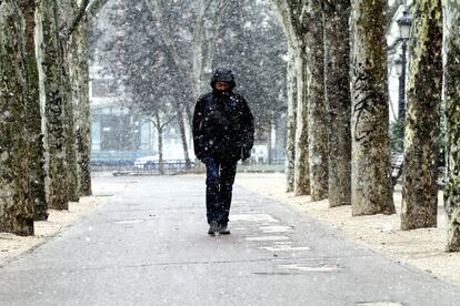 Un peatón camina por Plaza De España en medio de la nevada. Según la Aemet, la cota de nieve se sitúa entre los 800 y 1.000 metros, aunque a primera hora ha bajado hasta los 700 metros, lo que ha provocado que la nieve, que ha caído durante la noche en la sierra madrileña, haya hecho también acto de presencia en la capital.