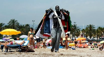 Un "mantero" ofreciendo sus productos en la playa de Vila-seca