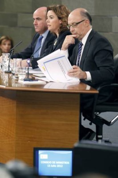 La vicepresidenta del Gobierno, Soraya Sáenz de Santamaría, junto a los ministros de Economía, Luis de Guindos (izda), y Hacienda, Cristóbal Montoro, durante la rueda de prensa que ofrecieron al término de la reunión del Consejo de Ministros, en el Palacio de la Moncloa.