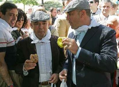Rafael Simancas y Miguel Sebastián, con gorra y pañuelo y saboreando una rosquilla en la pradera de la Ermita del Santo.