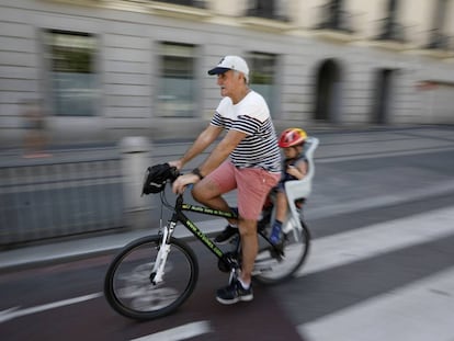 Un se&ntilde;or mayor circula con un ni&ntilde;o peque&ntilde;o en el transport&iacute;n por el carril bici de la calle de Alcal&aacute; de Madrid. 