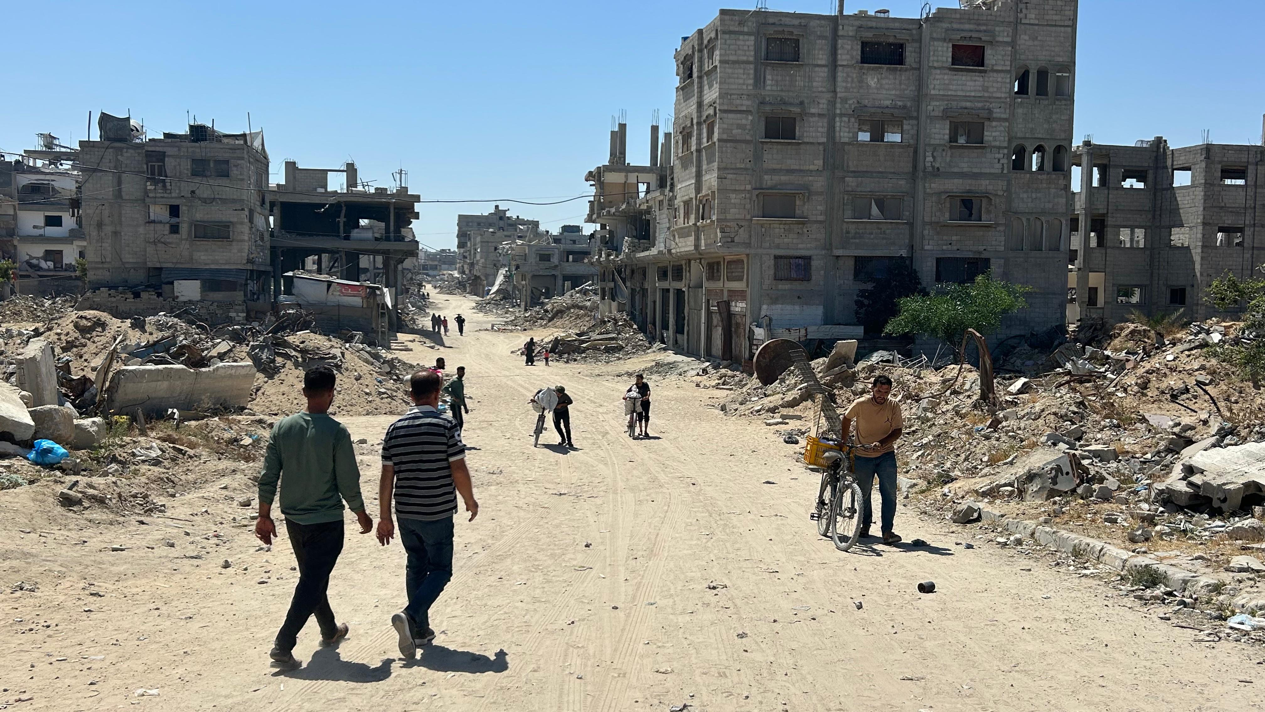 Ayman Abdel Bari (derecha) regresa de las ruinas de su casa en Jan Yunis tras haber conseguido varias latas de comida y enseres con los que sobrevivir algunos días más en su campo de desplazados.