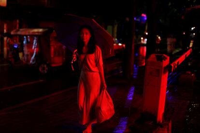 Una mujer camina en una calle iluminada con neón en el antiguo distrito de la ciudad de Liwan.