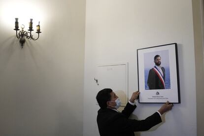 Un empleado presidencial cuelga el retrato oficial del nuevo presidente de Chile, Gabriel Boric, en la oficina del Palacio de La Moneda, el día de su toma de posesión.