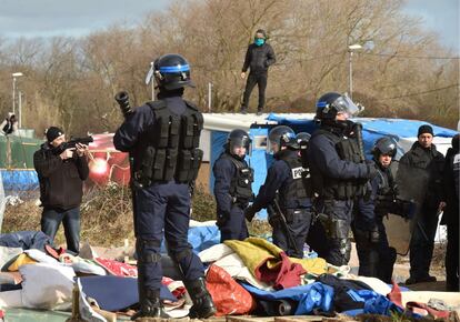 Las autoridades francesas han iniciado esta mañana el desmantelamiento de una parte del campamento de Calais. En la llamada Jungla de Calais viven en condiciones insalubres más de 3.000 refugiados a la espera de poder cruzar el canal de la Mancha. En la imagen, un hombre en una chabola mientras los policías antidisturbios desmantelan parte del campamento.