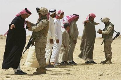 Dos <i>marines</i> de EE UU registran e identifican a los miembros de una familia iraquí en un puesto de control.