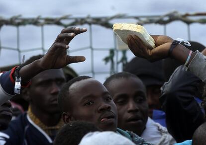 Inmigrantes comparten comida tras ser rescatados en las aguas del Mediterráneo, por un buque belga, cerca de las costas de Libia.