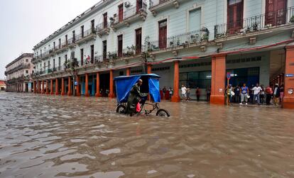 Un hombre empuja su bicitaxi por una calle inundada en La Habana por el paso del huracán en el oeste de Cuba. 
