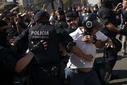 Un manifestante independentista es bloqueado por agentes de los Mossos d'Esquadra.