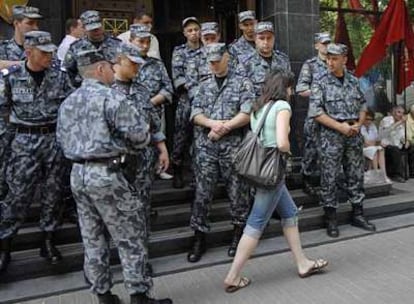 Una mujer pasa delante de miembros de las fuerzas especiales que vigilan la sede de la Fiscalía General de Ucrania ayer en Kiev.