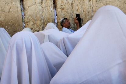 Un adorador judío graba con su teléfono móvil mientras otros, cubiertos con chales de oración, participan en una bendición sacerdotal durante la festividad judía de Sucot en el Muro de los Lamentos, en la Ciudad Vieja de Jerusalén.