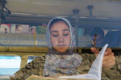 Una niña lee un libro en una librería móvil de Kabul (Afganistán).