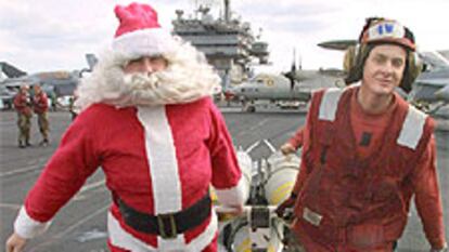 Un soldado vestido de Papá Noel ayuda a trasladar bombas a un avión.