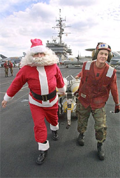 Un soldado vestido de Papá Noel ayuda a trasladar bombas a un avión.
