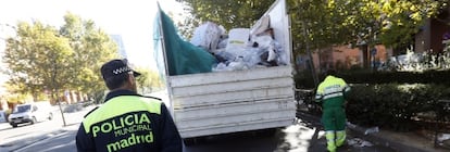 Un polic&iacute;a escolta a un barrendero en servicios m&iacute;nimos.