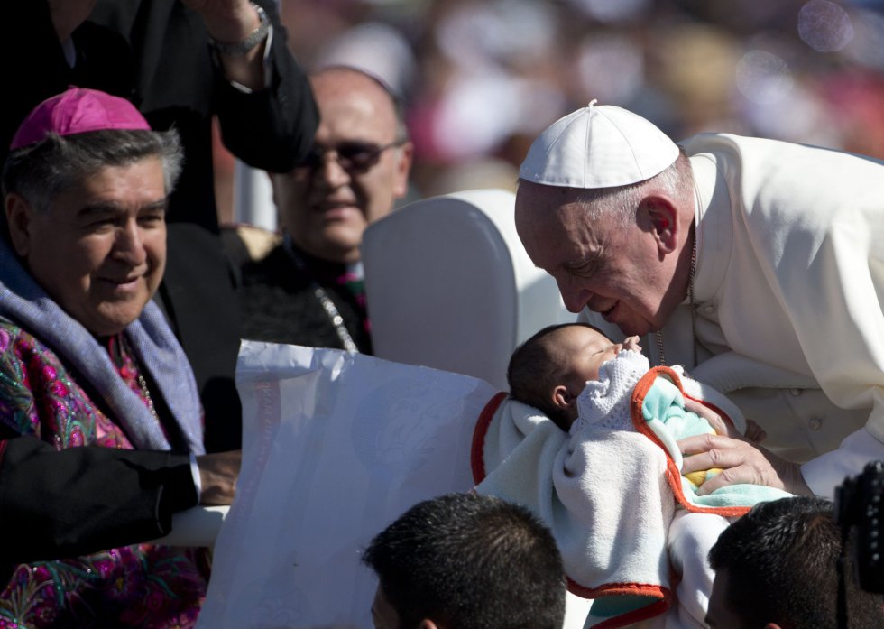 El papa Francisco besa a un bebé desde su papamóvil en San Cristóbal de las Casas.