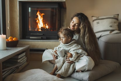 Una madre y su hija disfrutan del cálido ambiente de un salón con chimenea.